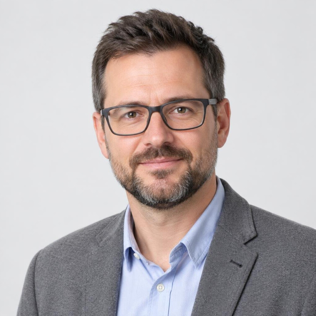 Studio portrait of a man with glasses and a beard in a casual blazer
