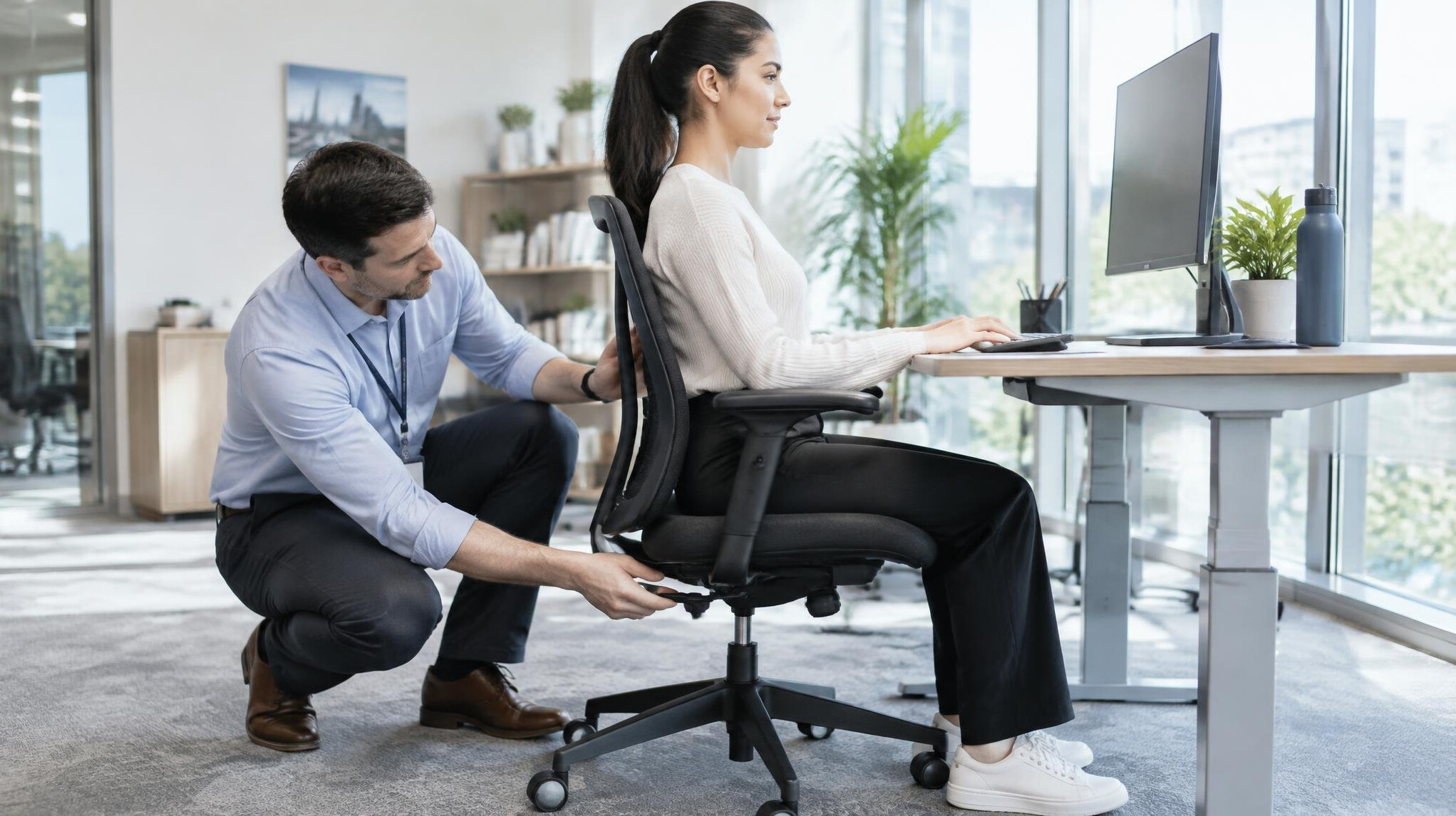Consultant adjusting an employee's office chair for better posture