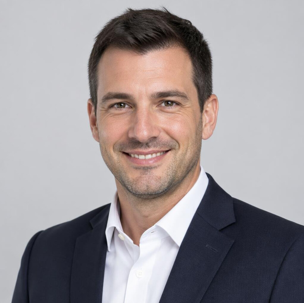 Studio portrait of a smiling man with short dark hair in business attire